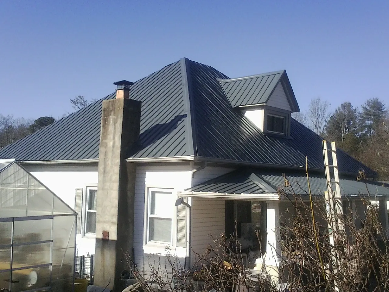 Dark blue standing seam metal roof on a white farmhouse with dormer — Slate & Tile Roof Repair by Roofing Brothers in Talking Rock