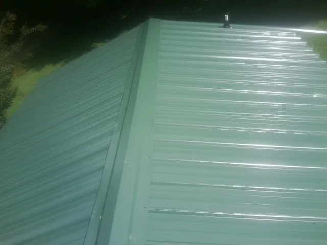 New green metal panels meeting at the ridge of a roof — Flat Roof Repair work by our crew in Talking Rock