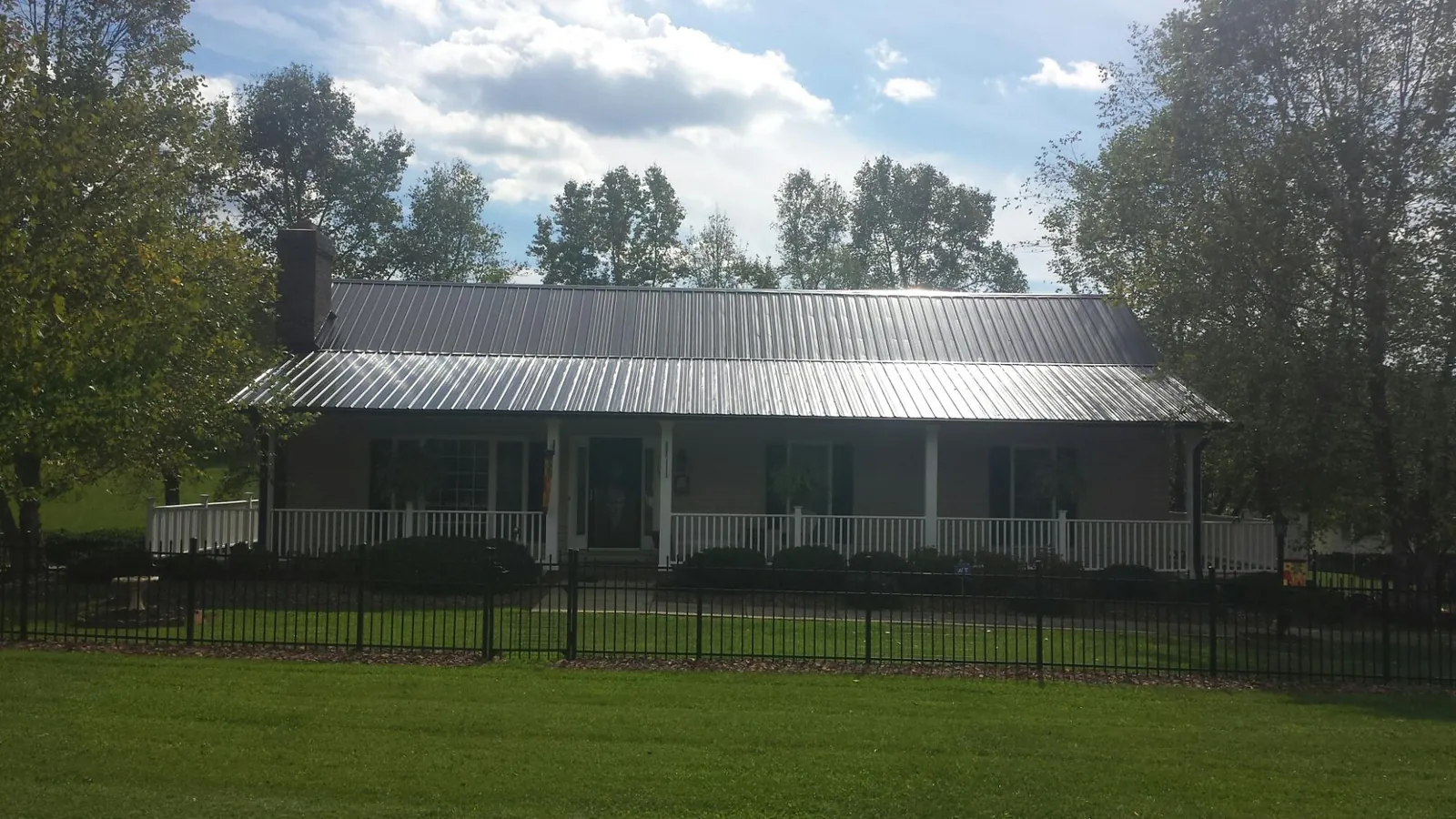 Gray metal roof on a brick ranch with a full width front porch — Gutter Guard Installation work by our crew in Talking Rock