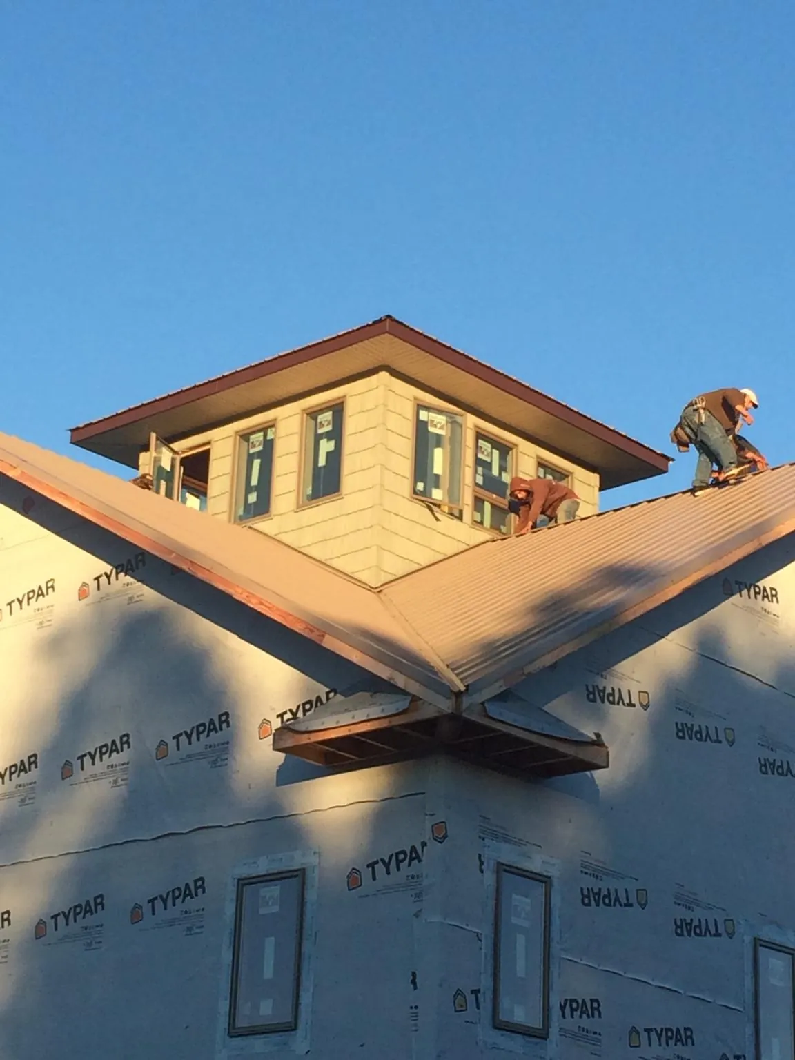 Roofers working around a rooftop cupola on a new metal roof at sunset — Roof Waterproofing in Talking Rock by Roofing Brothers